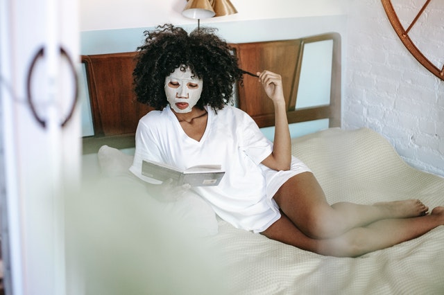 žena s kosmetickou maskou čte knížku